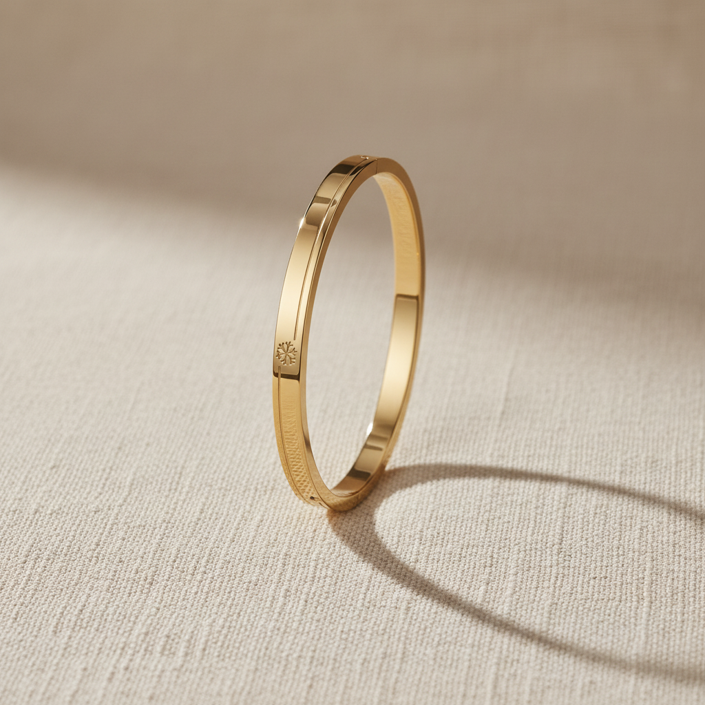 A realistic, natural daylight flat lay photograph of the premium gold plated oval snowflake engraved bracelet, sized specifically for thin wrists, resting beautifully on a textured cream linen cloth.