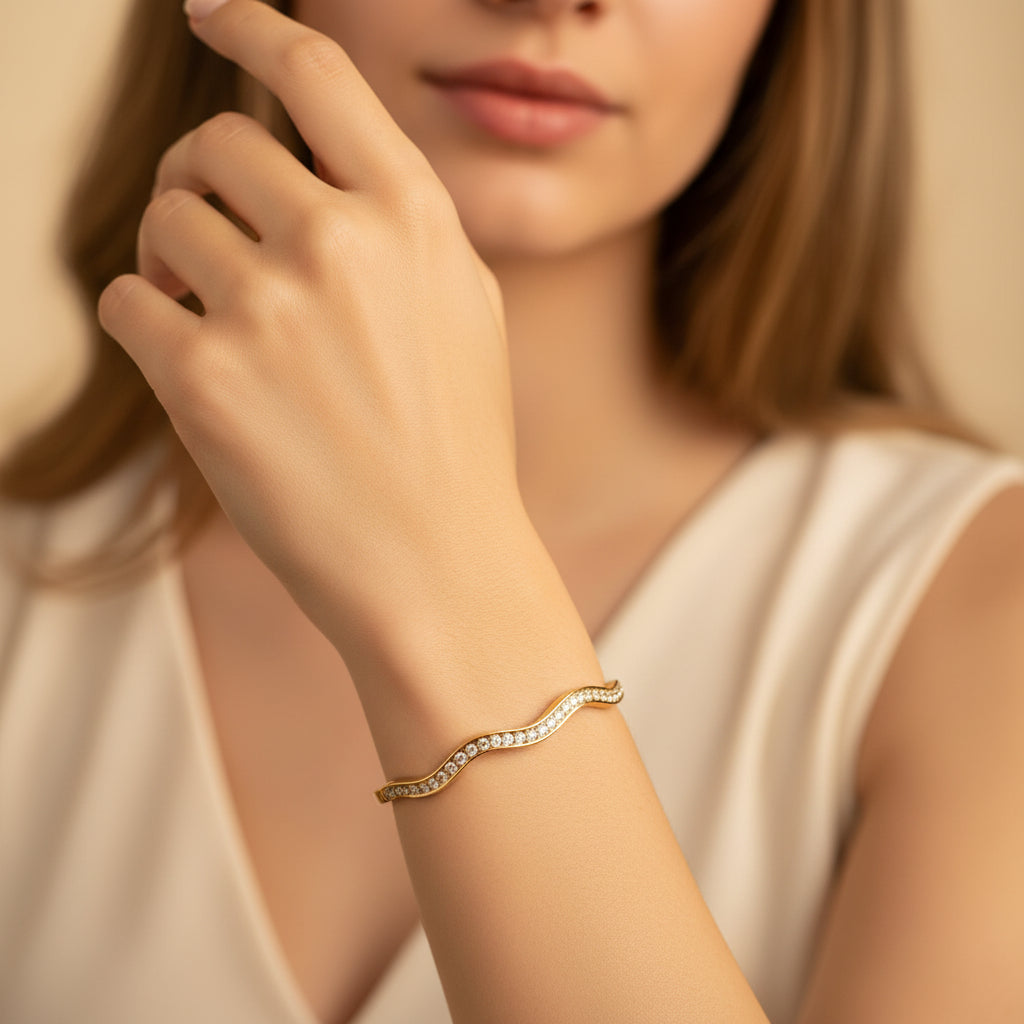 A close-up view of the Aura Stream Crystal Bangle showcasing the unique split-band gold design and the shimmering crystal path.