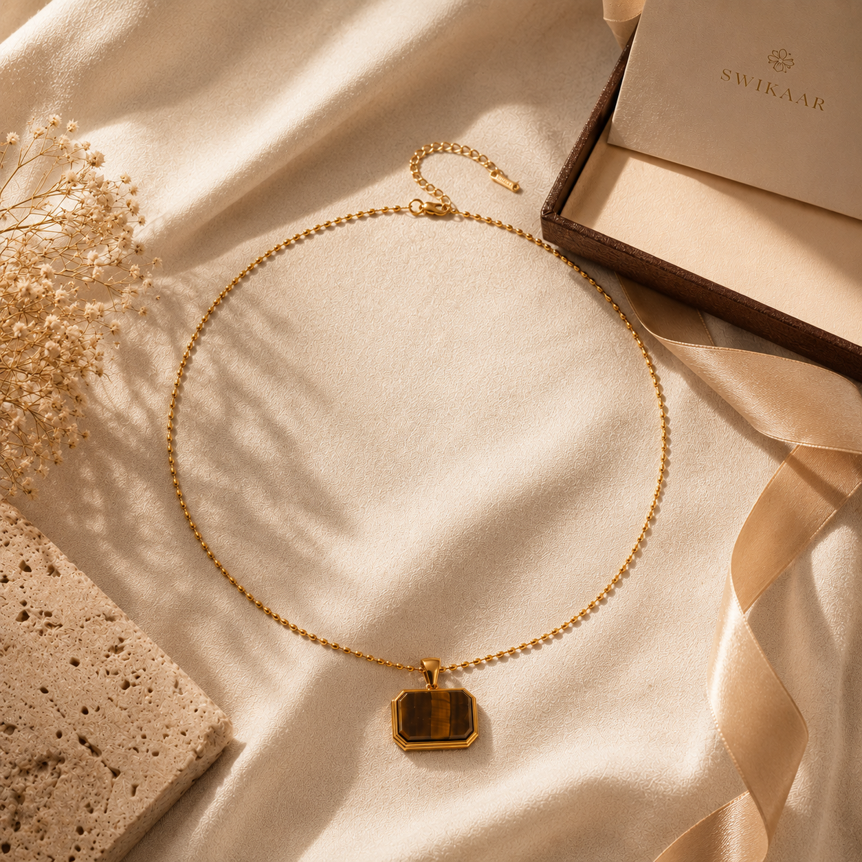 Tiger Eye pendant necklace styled on cream linen with luxury accessories.