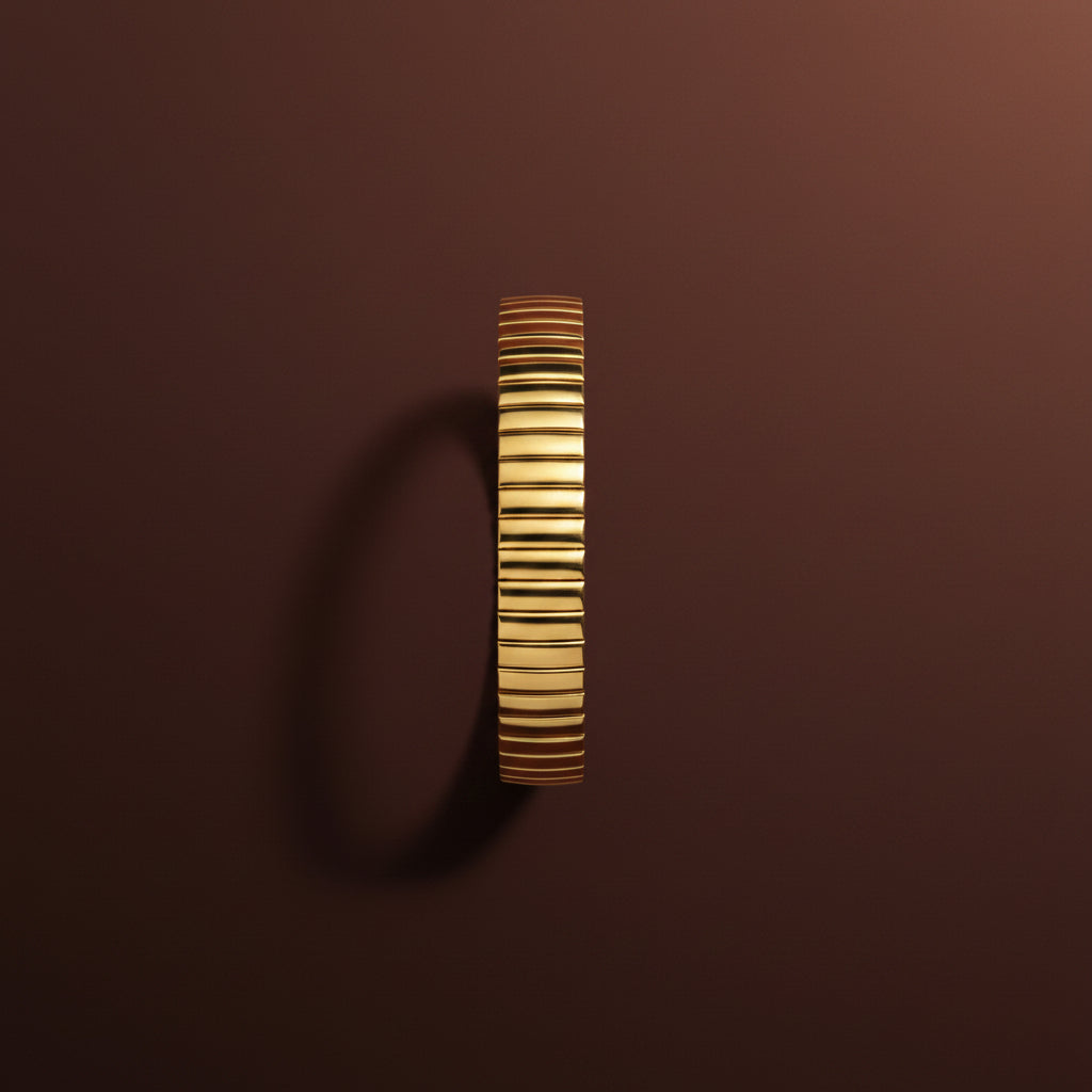 A detailed studio close-up of the Auric Cascade Flex Bracelet showcasing its textured, high-polish 18K gold finish and flexible construction.