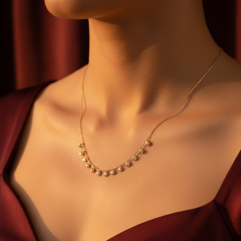 A detailed, realistic photograph focusing closely on a woman's neck, wearing the 18K gold plated bezel crystal droplet station ball chain necklace under warm golden lighting against a solid deep cocoa brown background.