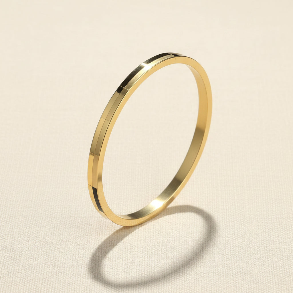 A professional standing catalogue view of the small size gold plated brick textured panel bangle for thin wrists, with clean shadows on a light cream background.
