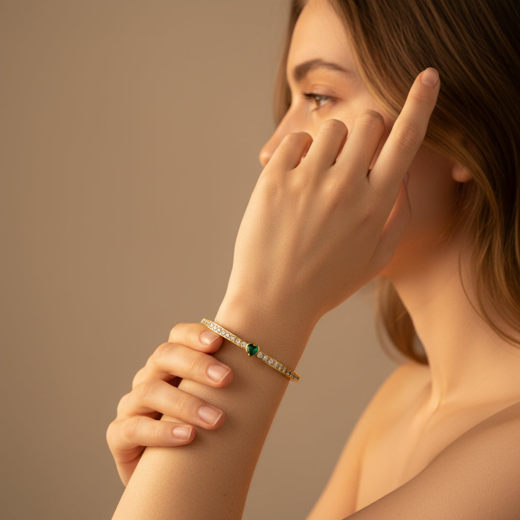 Gold bracelet with green gemstone on a white cushion