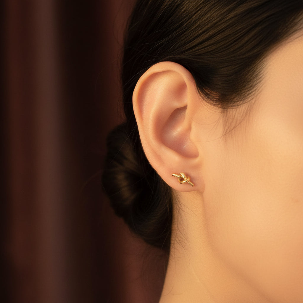 Woman wearing Eterna Knot Stud Earrings with focus on the knot design.