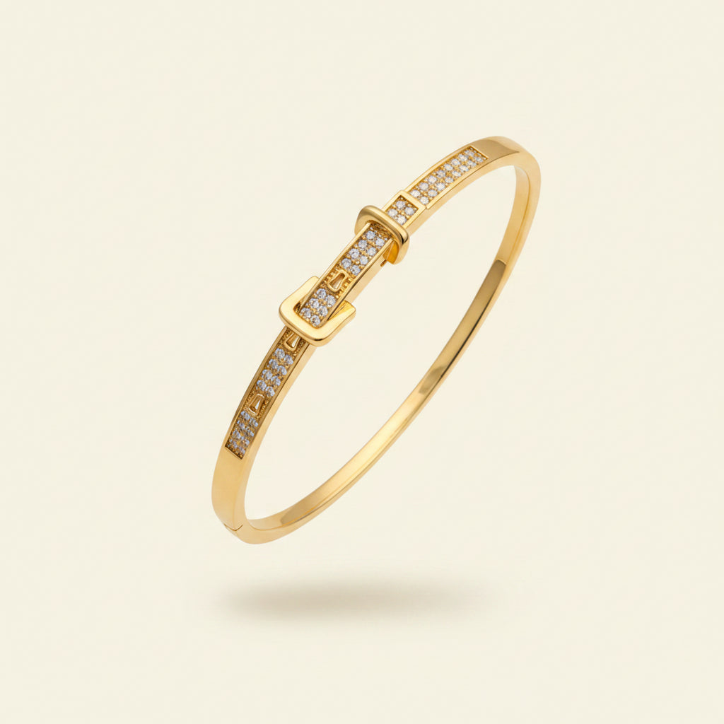 A professional standing catalogue view of the regular size 18K gold plated belt buckle crystal statement bangle with simple shadows on a light #f5f3eb cream background.