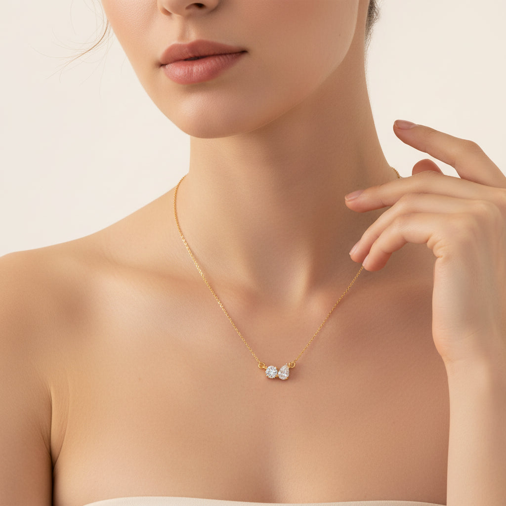 An appealing lifestyle photograph of a model showing her body and doing a hand pose, highlighting the sparkling gold two stone crystal pendant necklace under highly clear lighting.