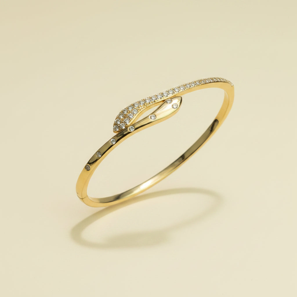 A professional standing catalogue view of the 18K gold plated overlapping snake wrap kada bangle with simple shadows on a light #f5f3eb cream background.