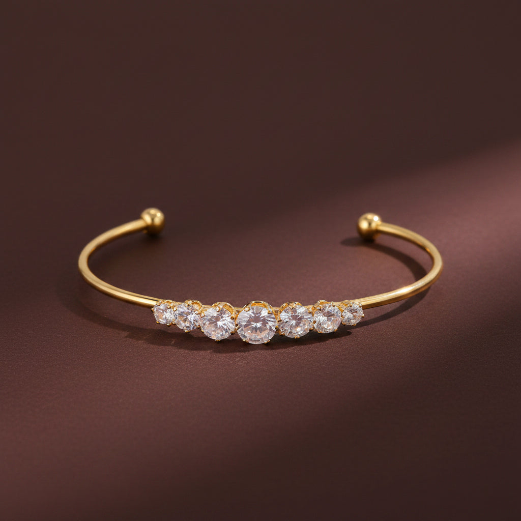 Professional catalogue flat lay of the Aria graduated crystal open cuff Kada bangle with soft shadows on a rich brown background.