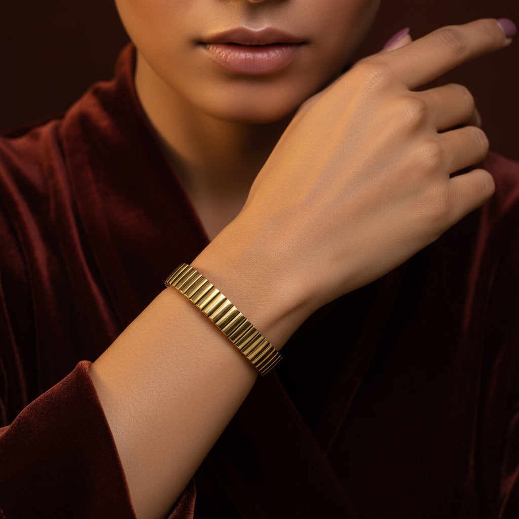 A model's wrist wearing the Auric Cascade Flex Bracelet to demonstrate how it flexibly contours to the skin and catches the light.