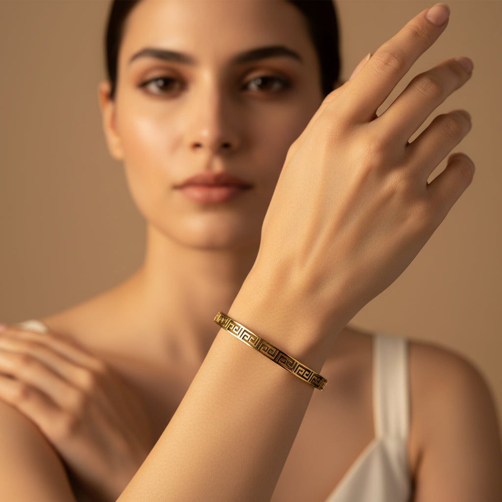 A model's wrist wearing the Regal Key Bangle to showcase its size, profile, and elegant golden luster.
