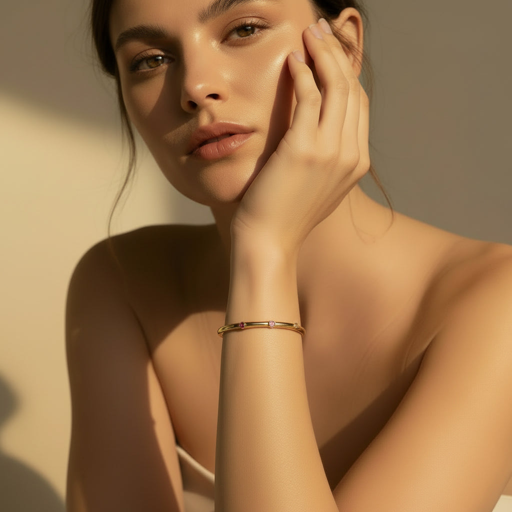 A model's wrist wearing the Pink Stone Gold Bangle to demonstrate its soft color and elegant, structured fit.