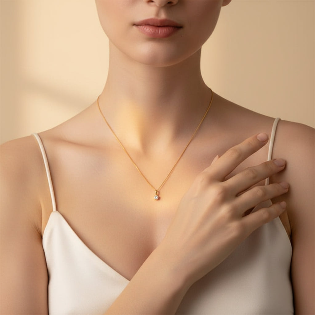 An appealing lifestyle photograph of a model in a pose with her hand, showcasing the minimal round solitaire bezel pendant necklace under dramatic lighting against a minimal, light background.