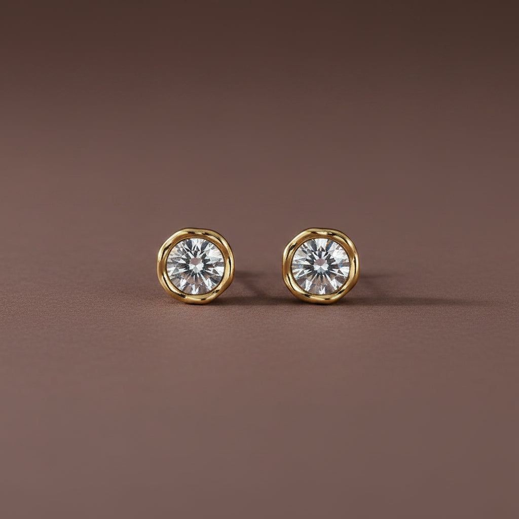 Professional catalogue flat lay of the Siren molten gold solitaire stud earrings with soft shadows on a rich brown background.