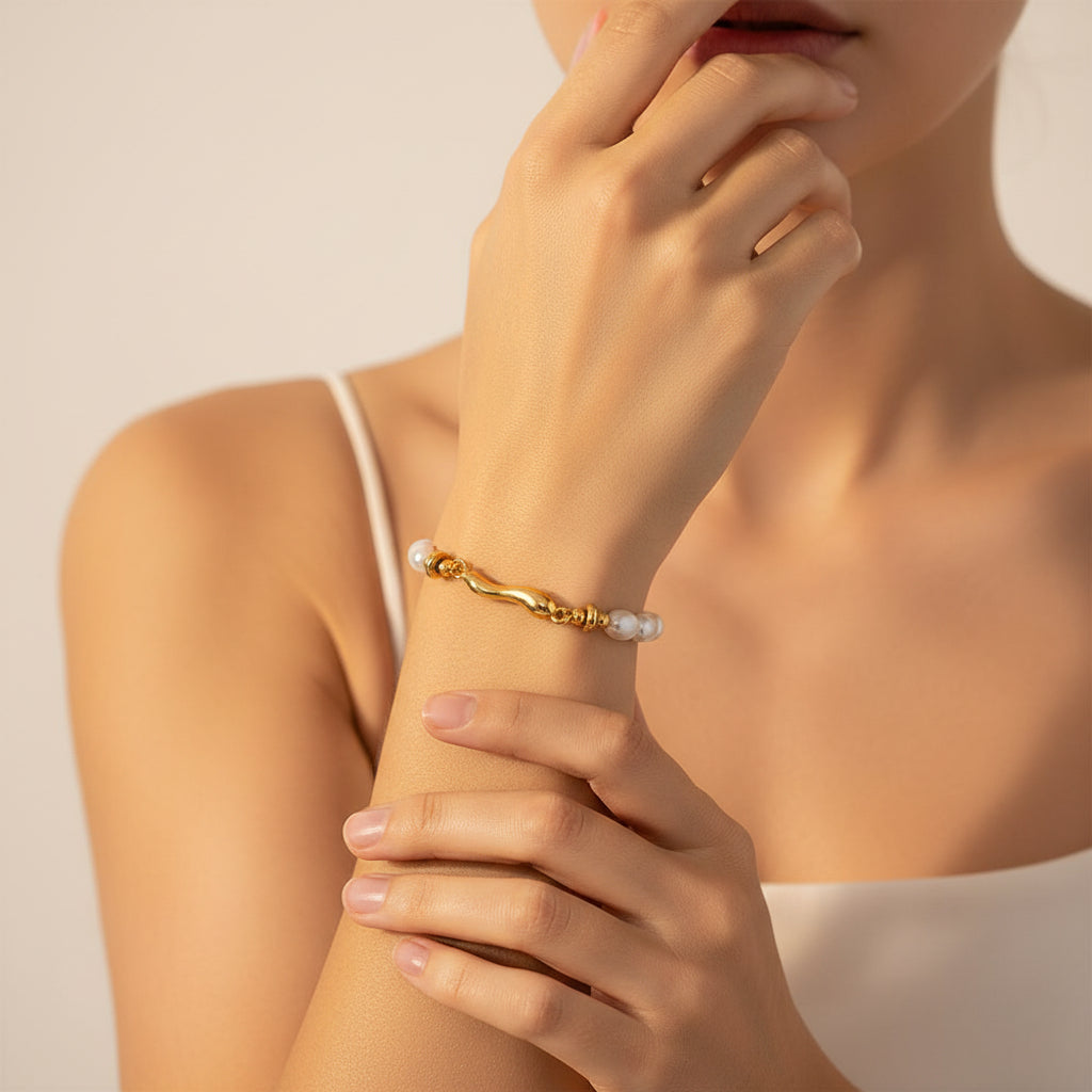 A high-end editorial lifestyle photograph capturing the sculptural gold wave pearl bracelet composed sharply and clearly on an appealing luxury food item.