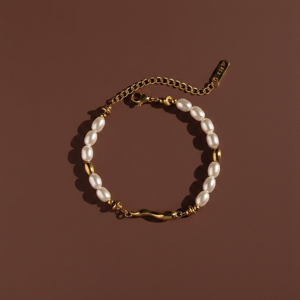 Professional catalogue flat lay of the 18K gold plated molten wave pearl bracelet arranged in a precise circle with clean shadows on a deep cocoa brown background.