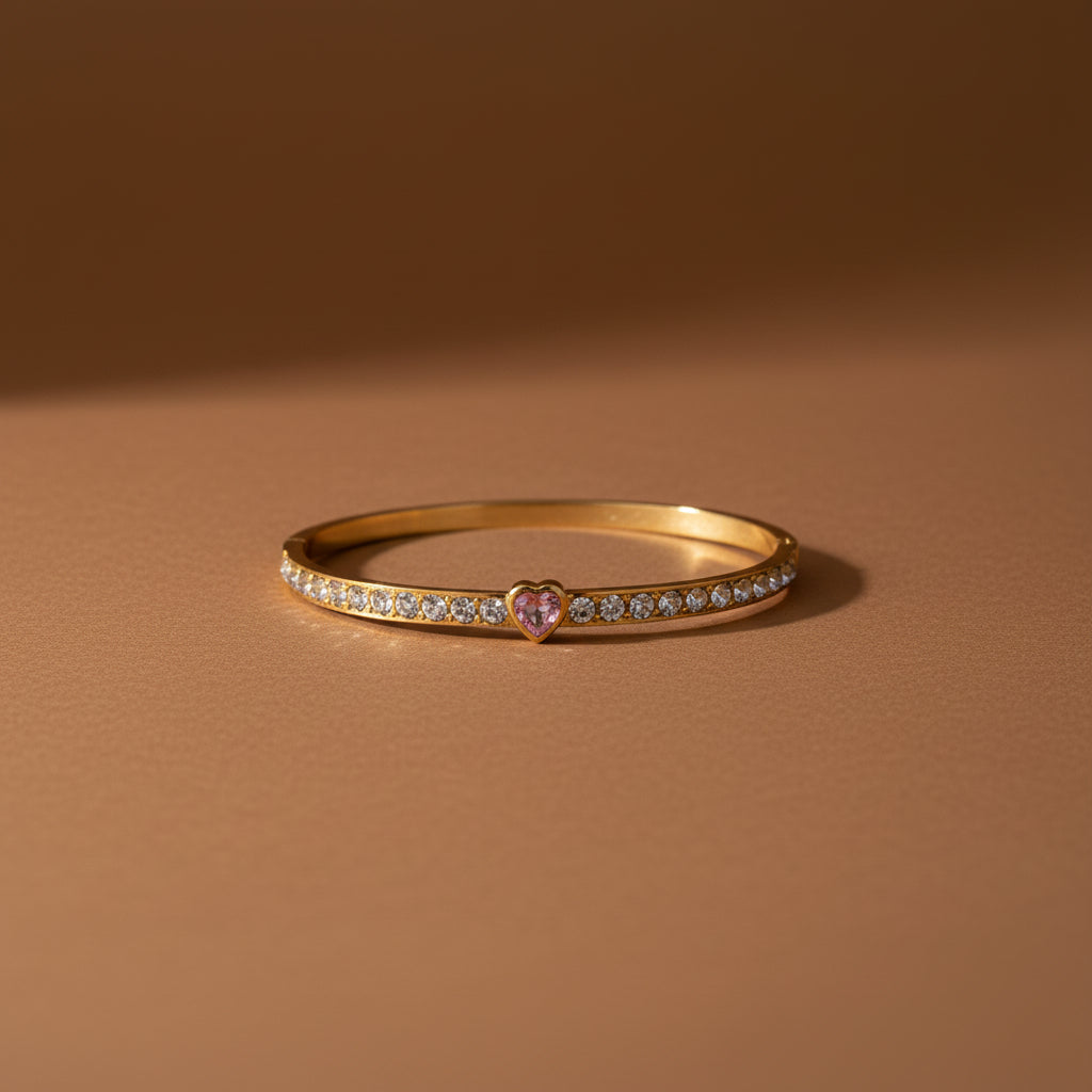 A close-up view of the Pink Heart Stone Gold Bangle highlighting the faceted pink heart gemstone and polished 18K gold finish.