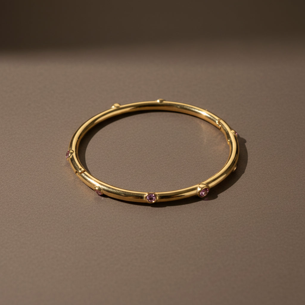 A close-up view of the Pink Stone Gold Bangle showcasing the delicate pink crystals and polished 18K gold-plated finish.