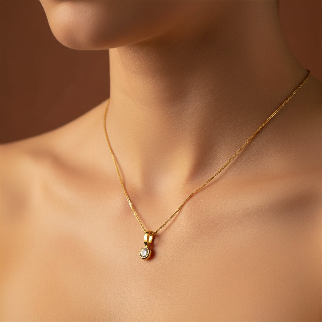 A detailed, realistic photograph focusing on a woman's neck, wearing the 18K gold plated floating round solitaire bezel necklace under warm golden lighting against a solid deep cocoa brown background.