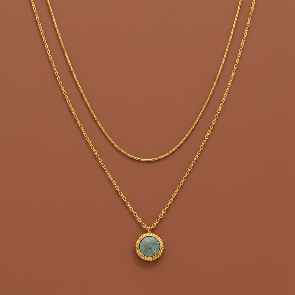 Layered gold necklace with sage green pendant displayed on a #f5f3eb luxury catalogue background.