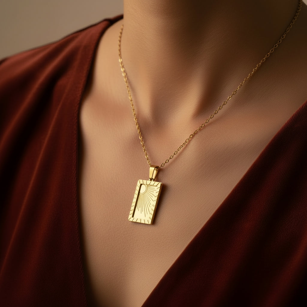 A detailed, realistic photograph focusing closely on a woman's neck, wearing the 18K gold plated tarot sun card pendant necklace under warm golden lighting against a solid deep cocoa brown background.