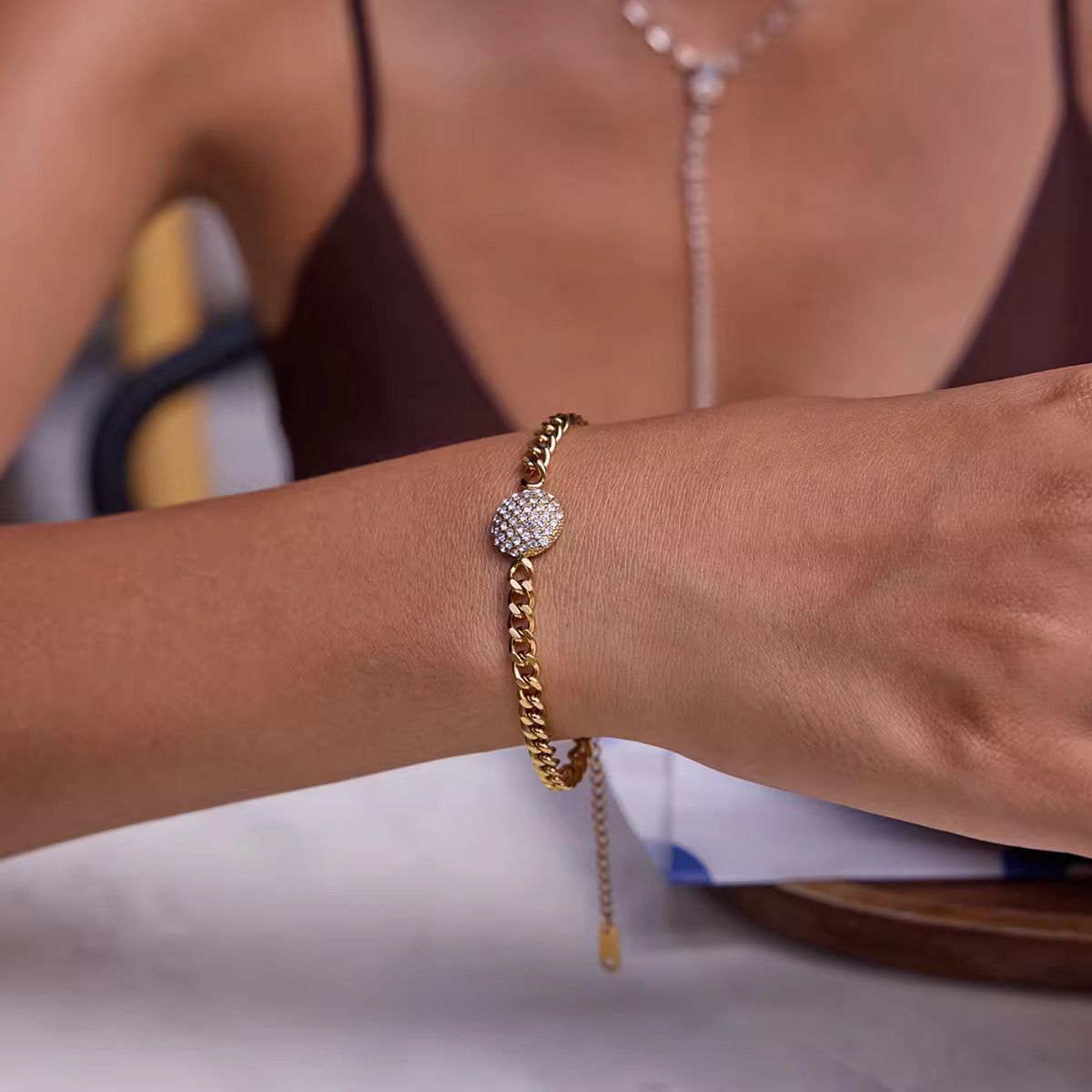 Realistic flat lay photograph of the premium gold crystal disc link bracelet resting on textured cream linen under crisp, natural sunlight.