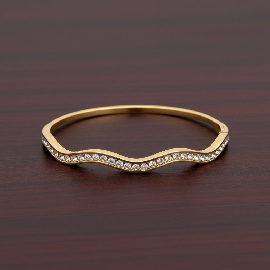 A close-up view of the Aura Stream Crystal Bangle showcasing the unique split-band gold design and the shimmering crystal path.