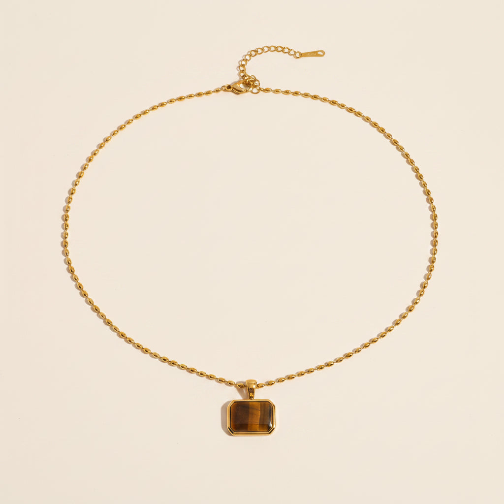 Gold Tiger Eye pendant necklace displayed on a #f5f3eb luxury catalogue background.