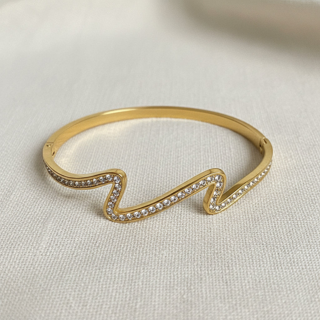 A high-resolution close-up of the Aurielle Crystal Wave Bangle highlighting the intertwining gold and crystal wave design.