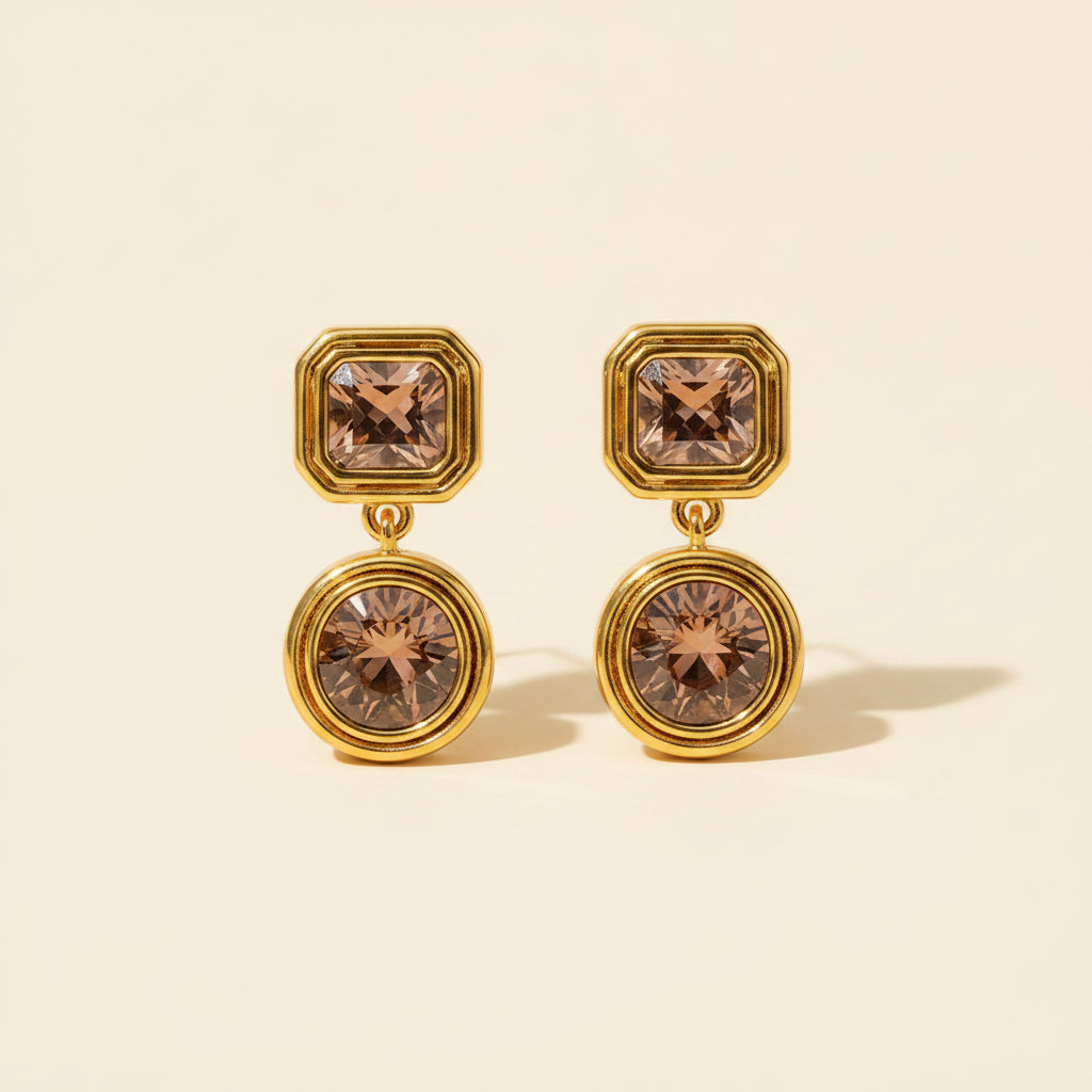 Gold champagne drop earrings on a premium cream catalogue background.