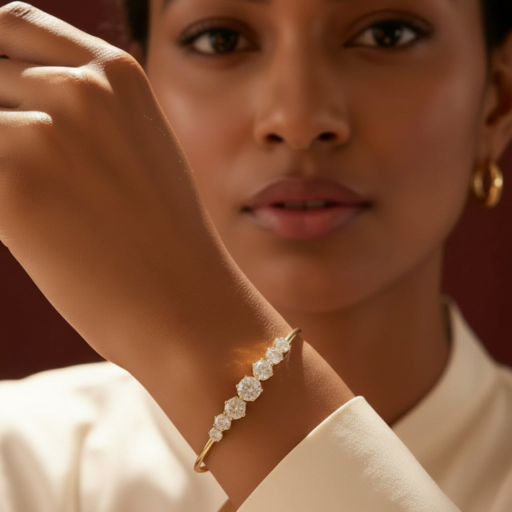 Zoomed-in flat shot of a model with her face half-visible, showcasing the gold graduated crystal Kada bracelet on her wrist against a rich brown background.