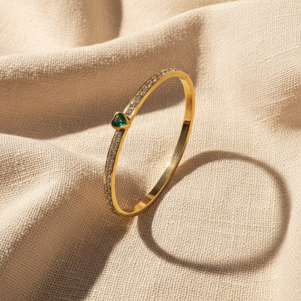 Gold bracelet with green gemstone on a white cushion