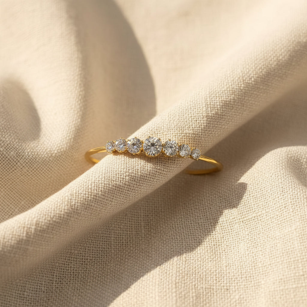A standing lifestyle photograph of a model with her face half-visible, highlighting the radiant gold graduated crystal cuff bangle on her wrist against a cream background.