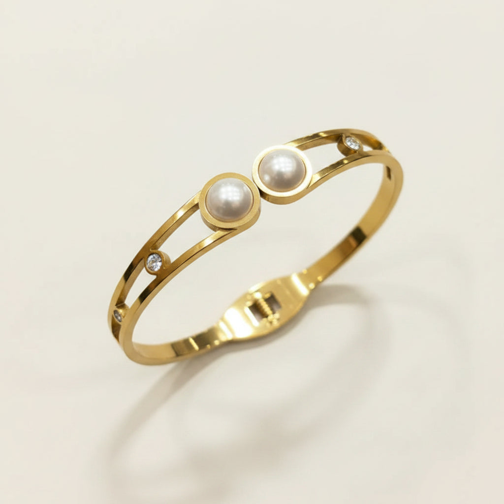 gold-cutout-pearl-bangle-bracelet-standing-cream-background