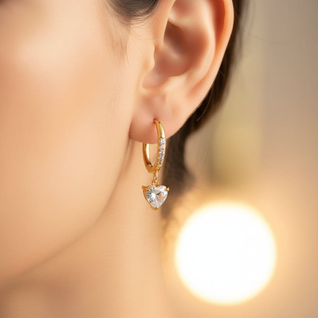 A model wearing the Heart Drop Hoop Earrings to demonstrate the elegant movement and size of the heart charms.