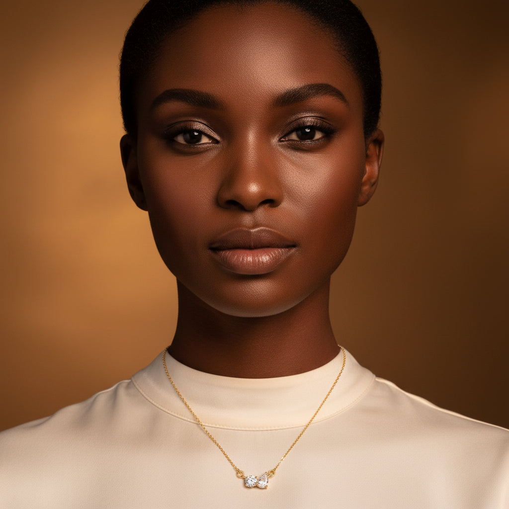 A stunning high-end e-commerce editorial photograph of a beautiful Black model under warm golden lighting, with her face fully visible and the focus centered sharply on the gold two stone crystal necklace.