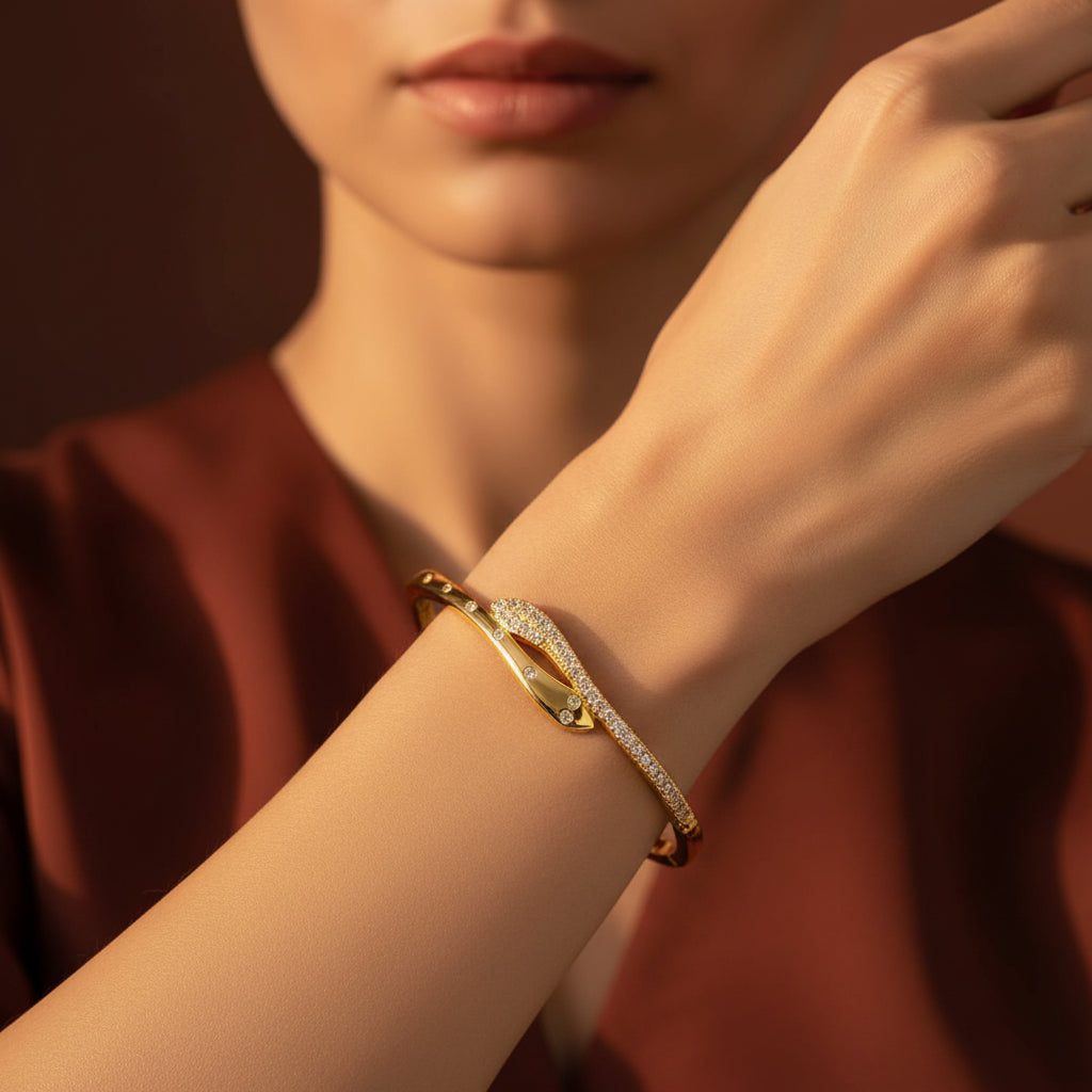 A close-up flat lay photograph focusing closely on a model's hand and wrist wearing the gold snake crossover wrap bracelet under warm golden lighting against a rich #5b3b3a brown background, as seen in IMG_4150.webp.