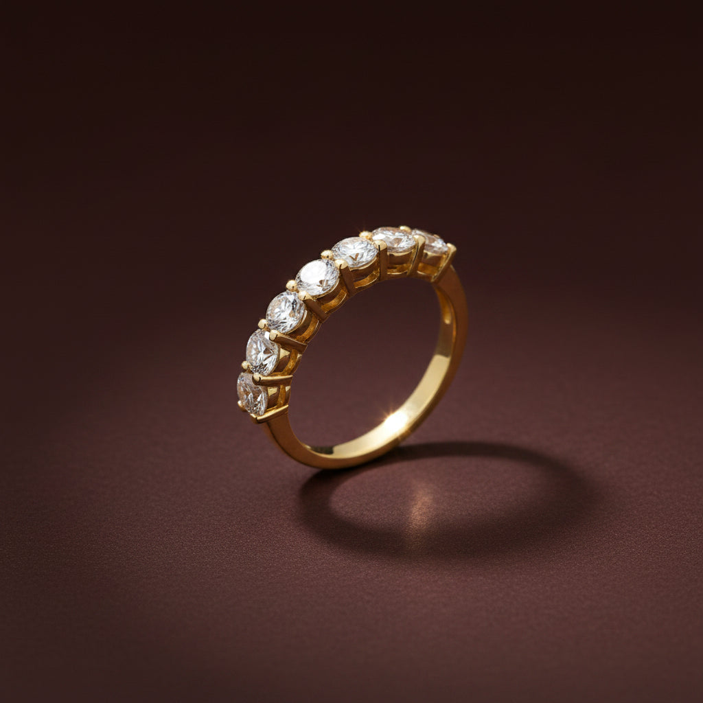 A professional high-angle flat lay catalogue shot of the gold plated seven stone crystal half eternity ring with simple shadows on a rich #5b3b3a brown background