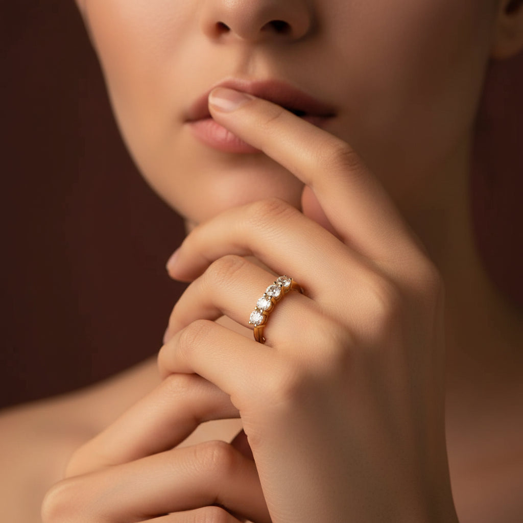 Zoomed-in flat layout of a model with her face half-visible, highlighting the gold seven-stone crystal stacker ring on her finger under warm golden lighting against a rich #5b3b3a brown background.