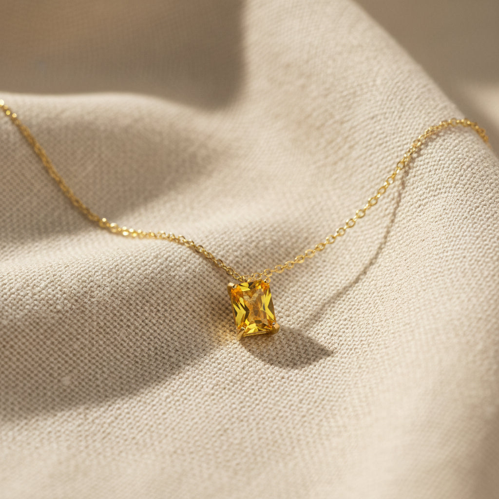 Detail shot of golden crystal pendant necklace catching light, gold-plated stainless steel