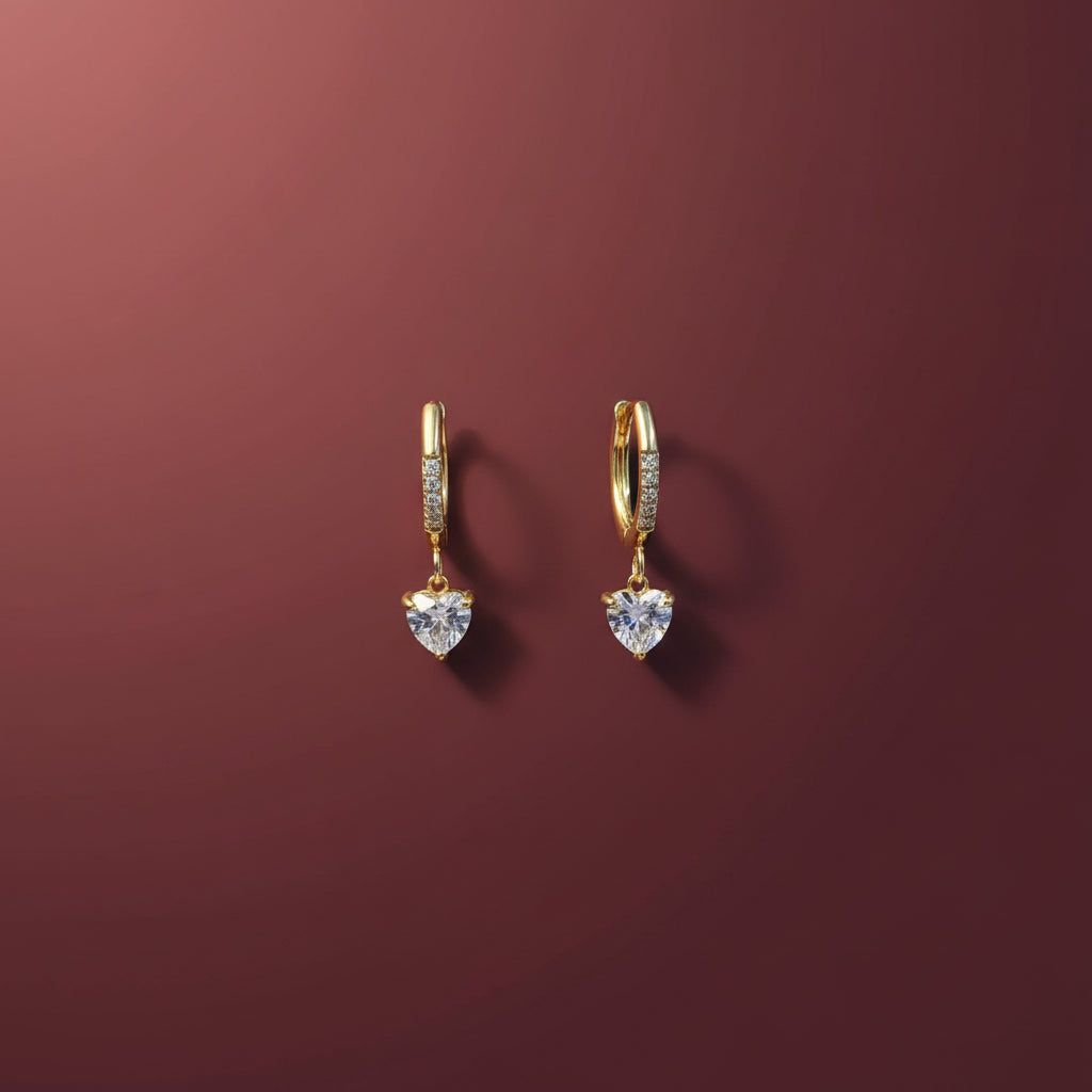 A close-up view of the Heart Drop Hoop Earrings highlighting the polished gold heart charms and hoop design.