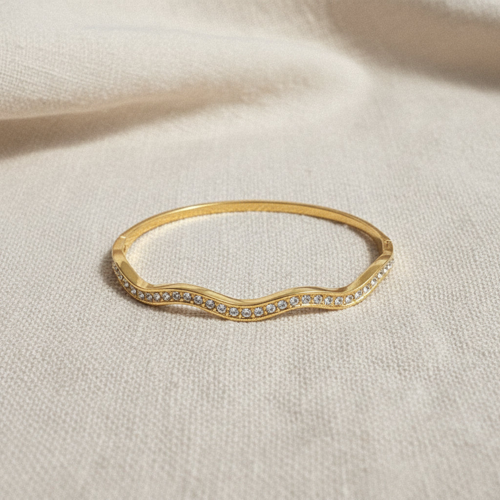 A model wearing the Aura Stream Crystal Bangle to showcase its airy, architectural silhouette and radiant golden luster.