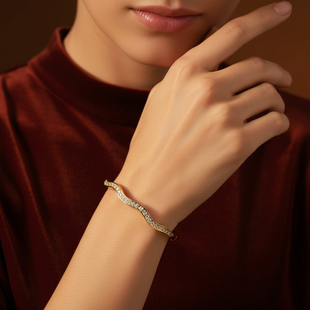 A model wearing the Aura Stream Crystal Bangle to showcase its airy, architectural silhouette and radiant golden luster.