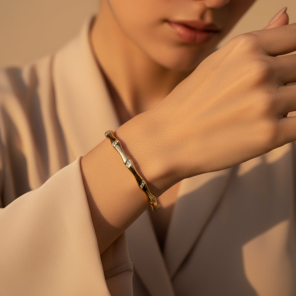A model's wrist wearing the Fluid Gold Bangle to showcase its unique sculptural silhouette and high-end luster.
