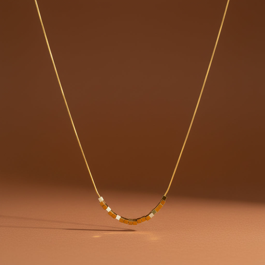 A model wearing the Minimal Gold Cube Necklace to demonstrate its sleek silhouette and how it sits on the neckline.