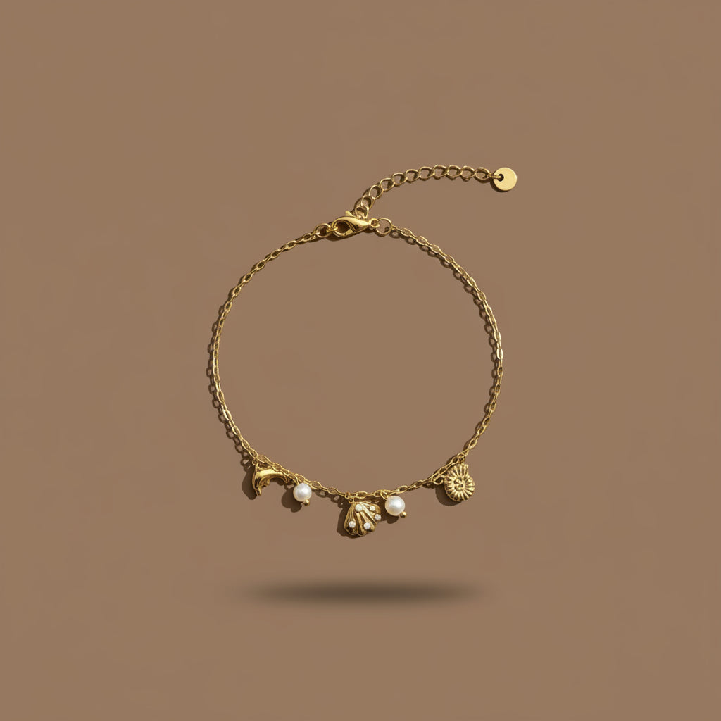 A detailed view of the Ocean Charm Bracelet featuring delicate sea-inspired charms and a brilliant gold finish.