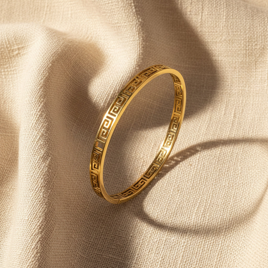 Gold bracelet with a geometric pattern on a white surface