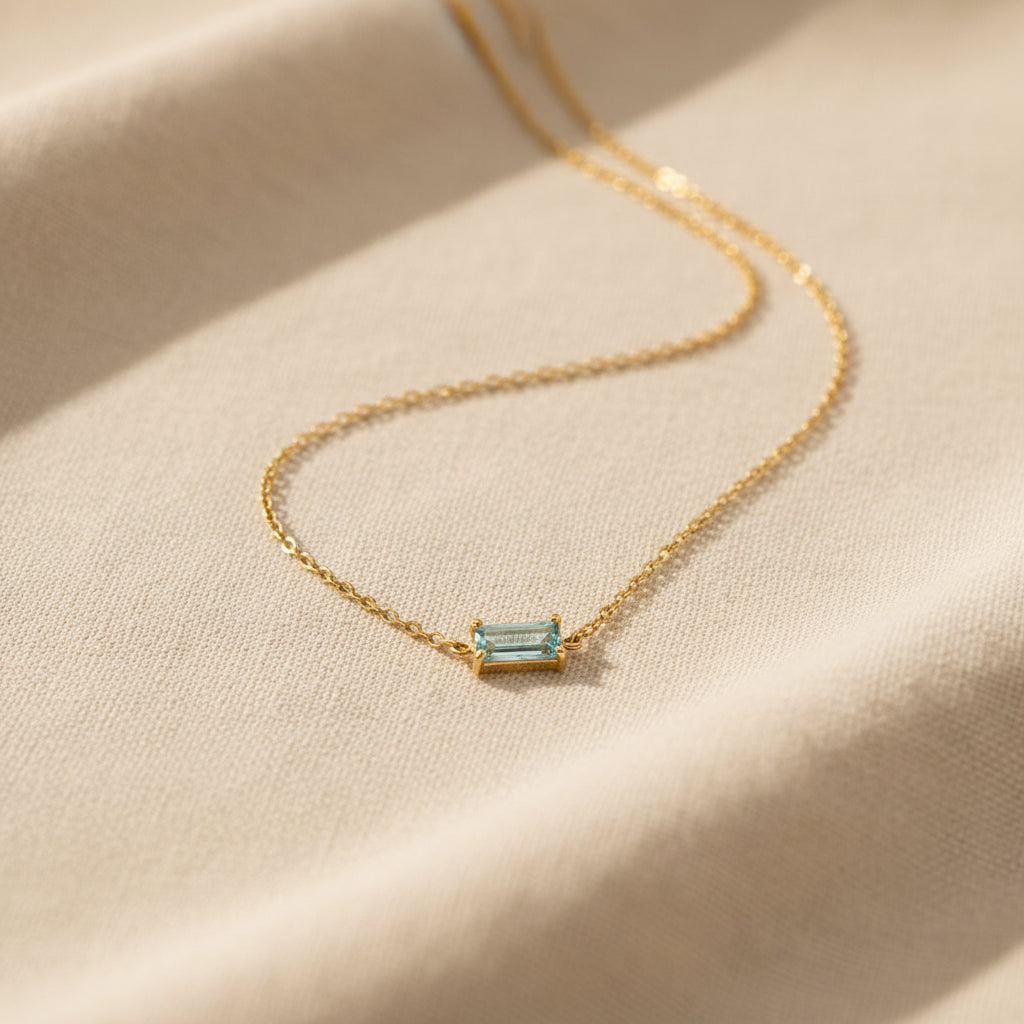 Blue crystal pendant necklace photographed on cream linen fabric.