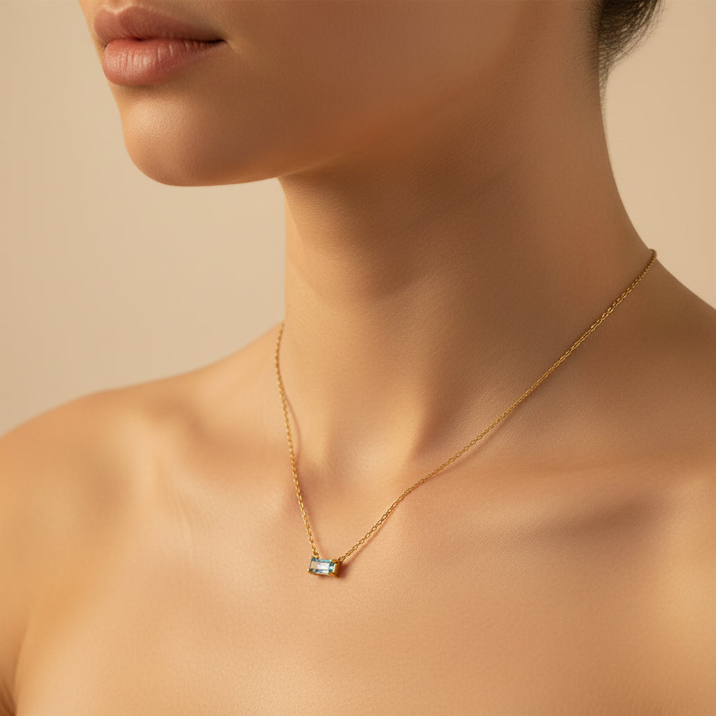 Model wearing an 18K gold plated blue crystal pendant necklace with focus on elegant neckline styling.