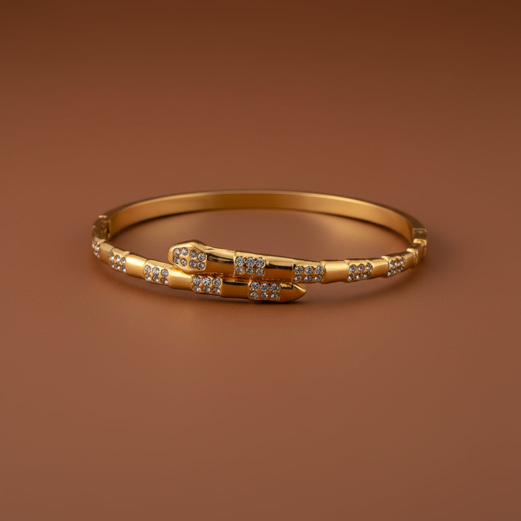 A detailed view of the Serpent Gold Bangle highlighting its sleek wrap-around design and 18K gold finish.