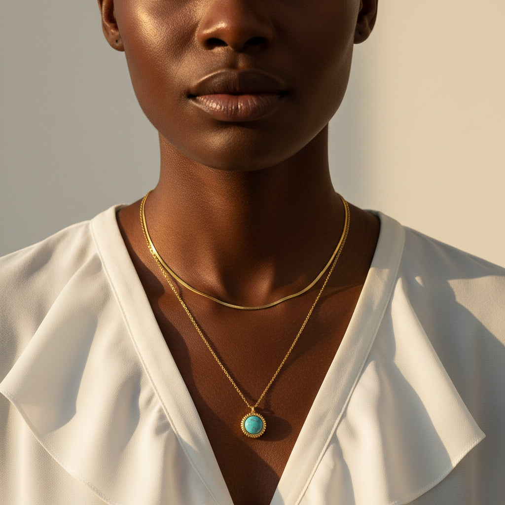 Black female model wearing an elegant layered gold necklace with a sage green pendant.